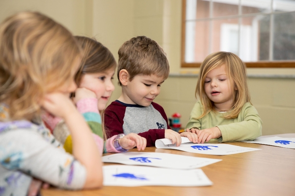 Preschool students draw at a table