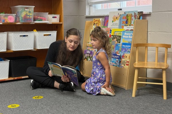 A preschool teacher reads with a student